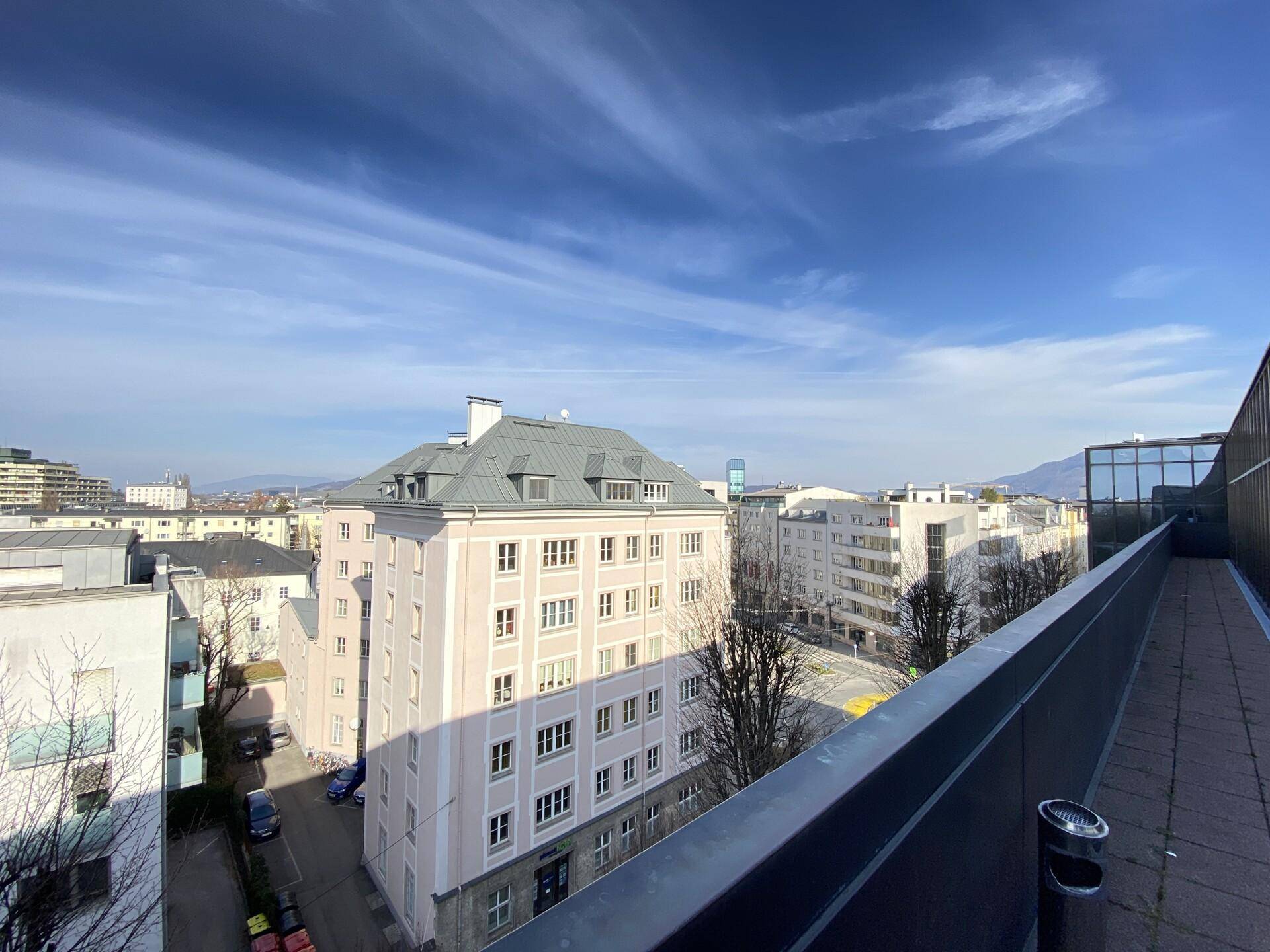 Panoramablick über die städtische Landschaft von einer erhöhten Position, mit verschiedenen Gebäudetypen unter blauem Himmel.