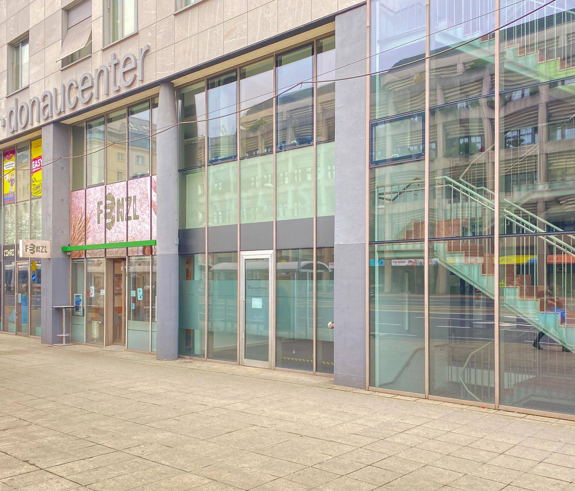 Ansicht der modernen Geschäftsfassade eines Einkaufszentrums mit großen Glasfenstern und Außentreppe.
