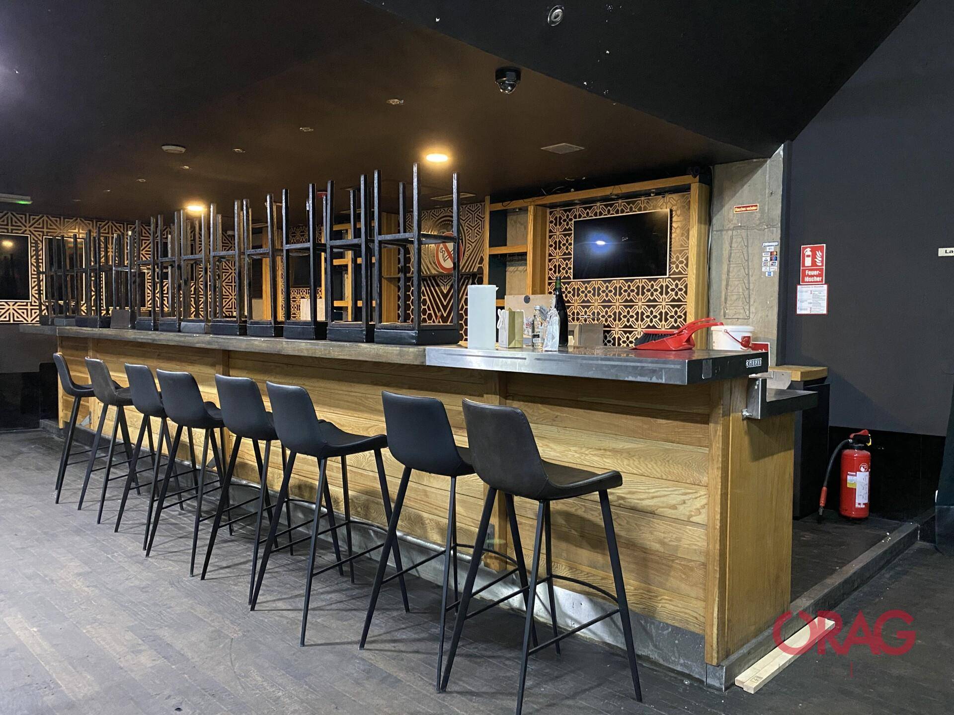 Lange Holzbar mit Barhockern und einer modernen Rückwand, ideal für Gastronomiebetriebe.