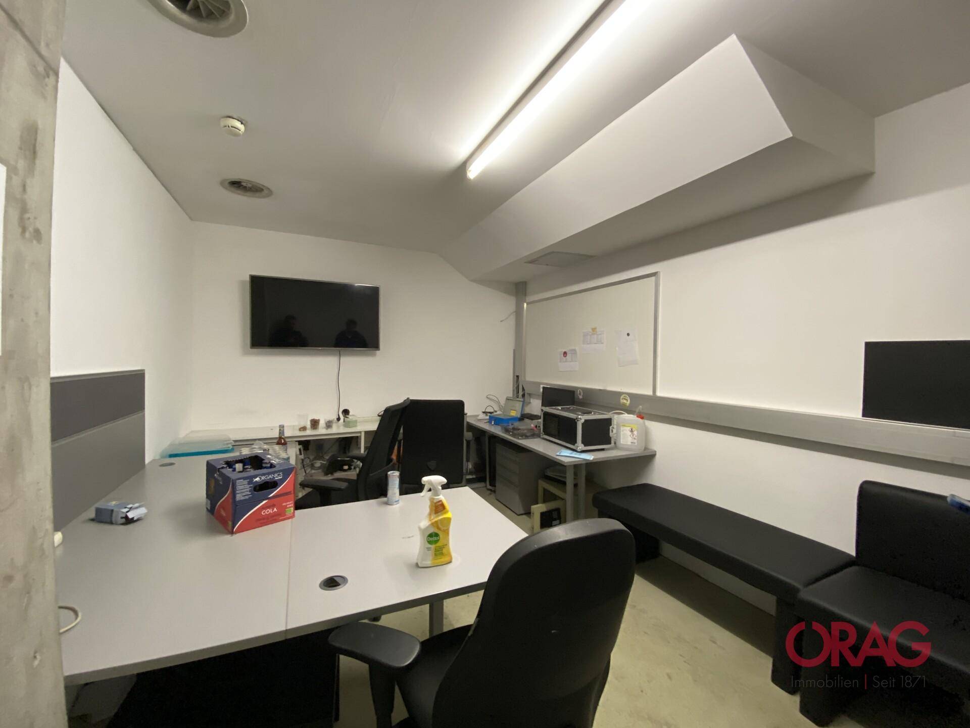 Modern eingerichtetes Büro mit Schreibtischen, Stühlen und einem Wandfernseher, ideal für Verwaltung.