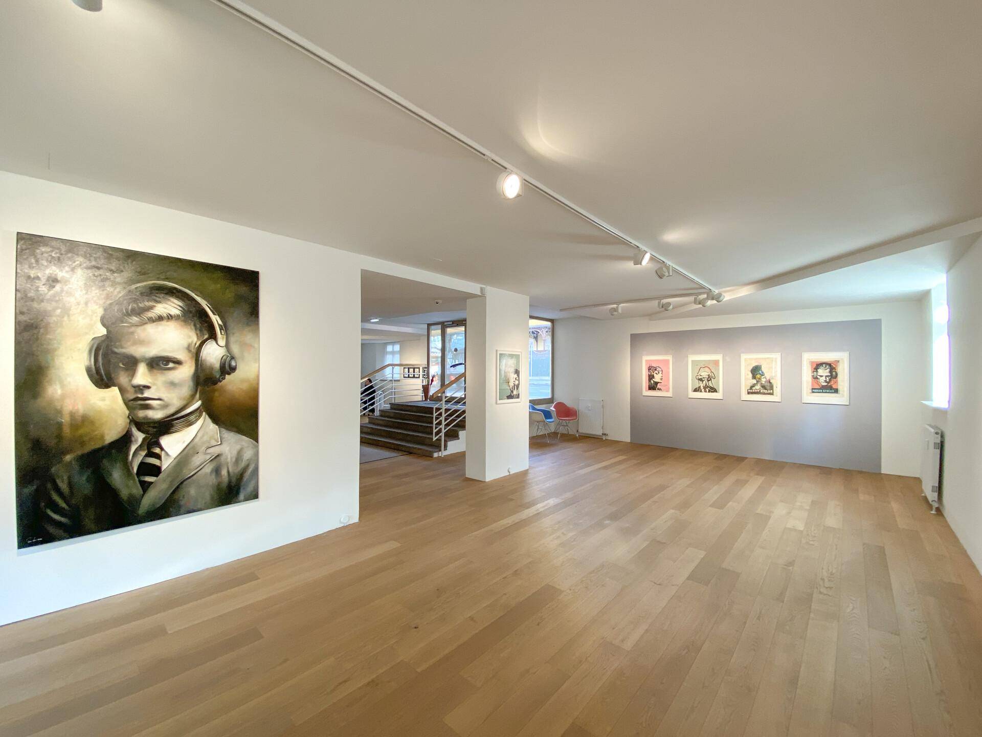 Heller und offener Ausstellungsraum mit Holzboden, modernen Kunstwerken und einer einladenden Atmosphäre.