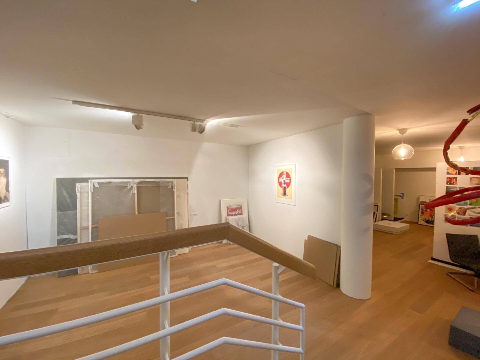 Lagerbereich der Galerie mit Kunstwerken, Kartons und einer Treppe, die nach unten führt.