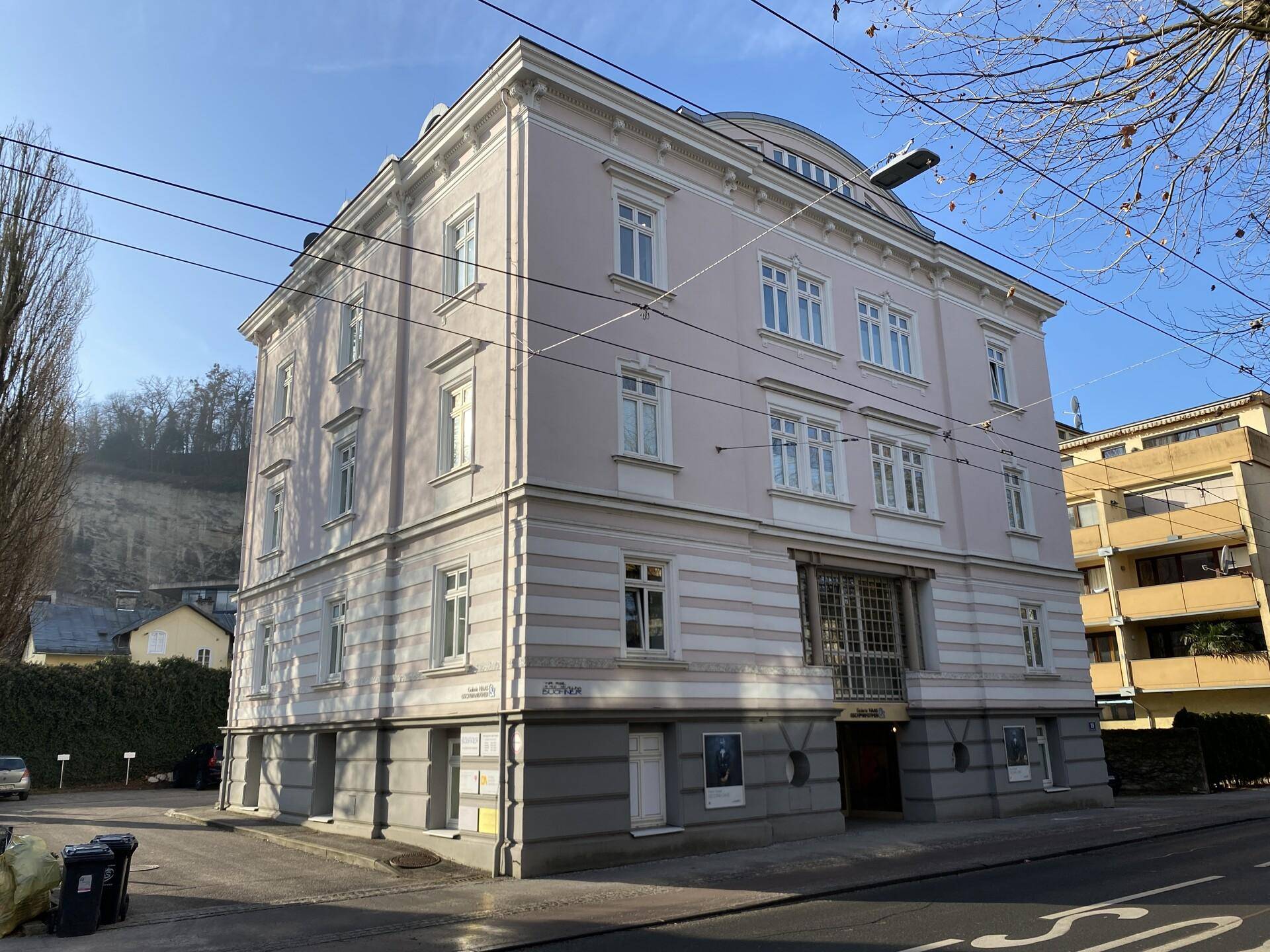 Gesamtansicht eines historischen Gebäudes mit mehreren Etagen und klassischer Architektur an einem sonnigen Tag.