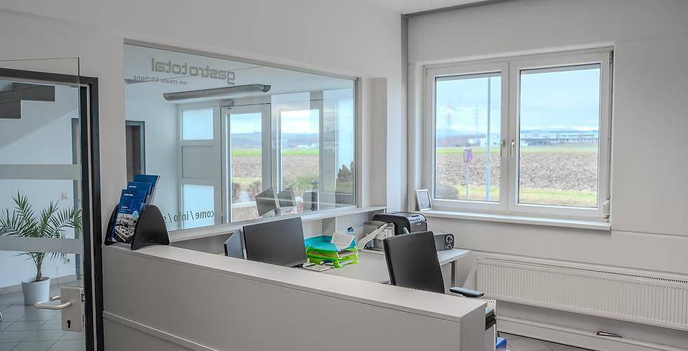 Freundlicher Empfangsbereich mit Schreibtisch und großen Fenstern, die einen weiten Blick auf die Landschaft bieten.