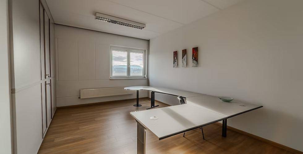 Ruhiges Einzelbüro mit Holzfußboden, großen Fenstern und minimalistischer Einrichtung, ideal für konzentriertes Arbeiten.