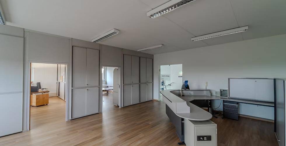 Offener Bürobereich mit modularen Trennwänden, Holzfußboden und einem Empfangstresen, der den Raum strukturiert.