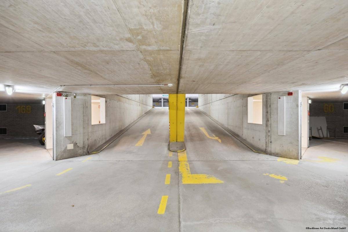 Einfahrt zur Tiefgarage mit Betonwänden, gelben Markierungen und klaren Fahrspuren.