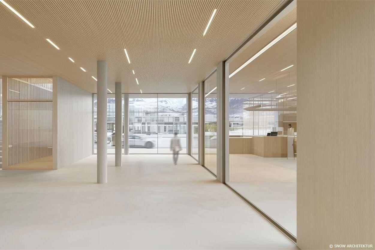 Geräumiger, heller Gemeinschaftsbereich mit großen Glasfronten, Holzakzenten und Blick auf die Umgebung.