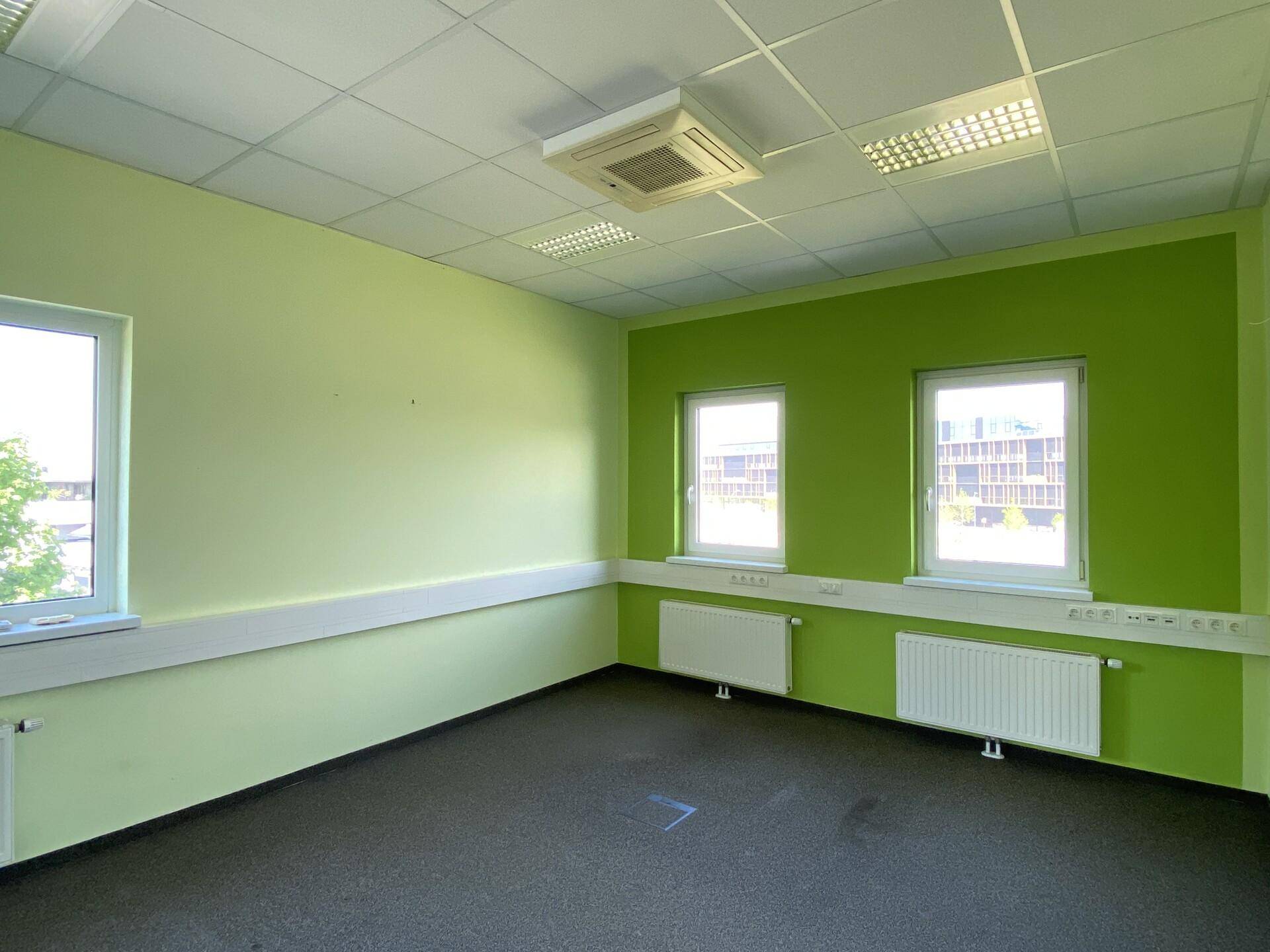 Modernes Büro mit hellgrünen Wänden, Teppichboden und Klimaanlage, bereit für die individuelle Gestaltung.