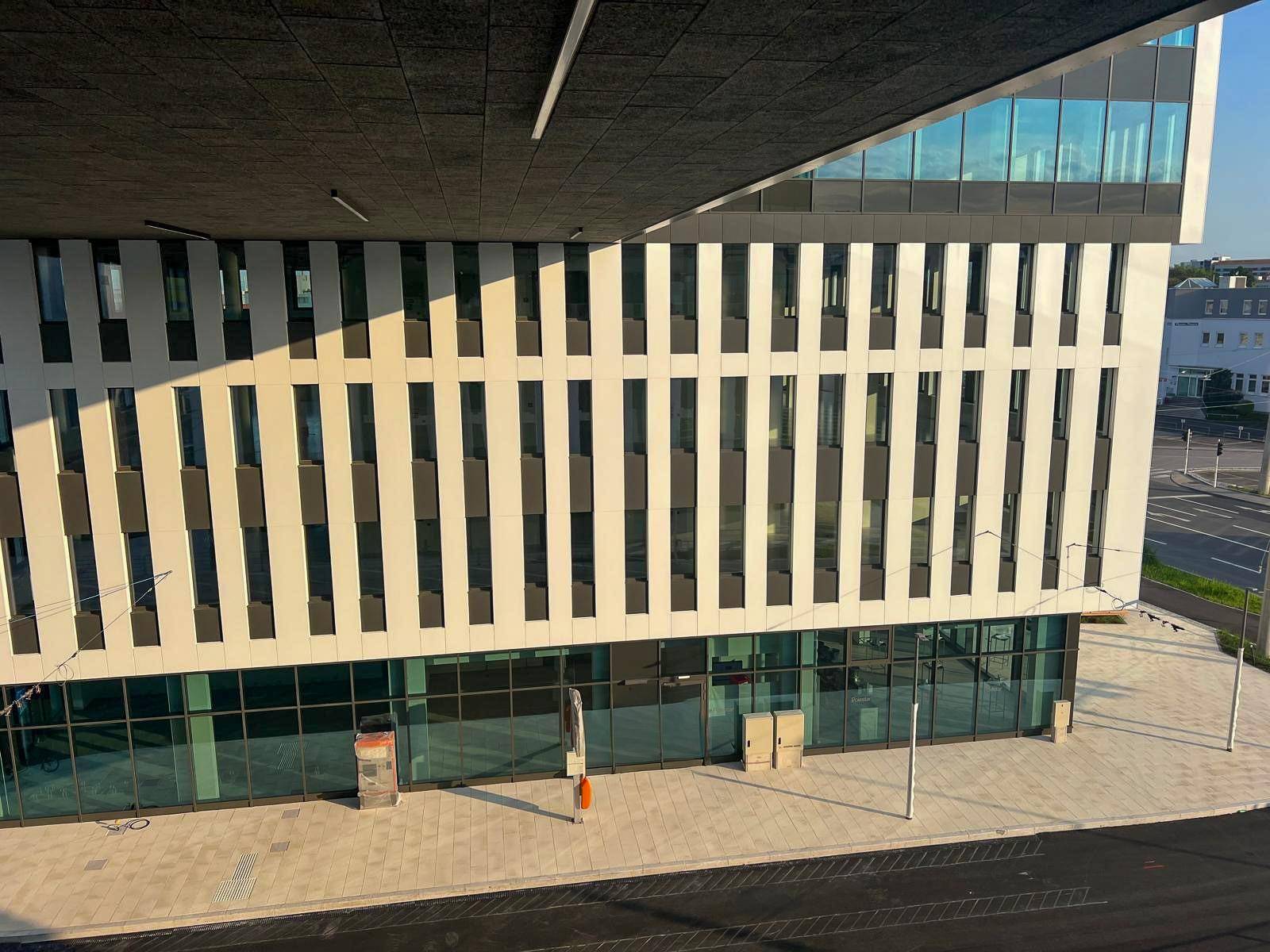 Die moderne Fassade eines Bürogebäudes mit großen Fenstern und Geschäftsflächen im Erdgeschoss.