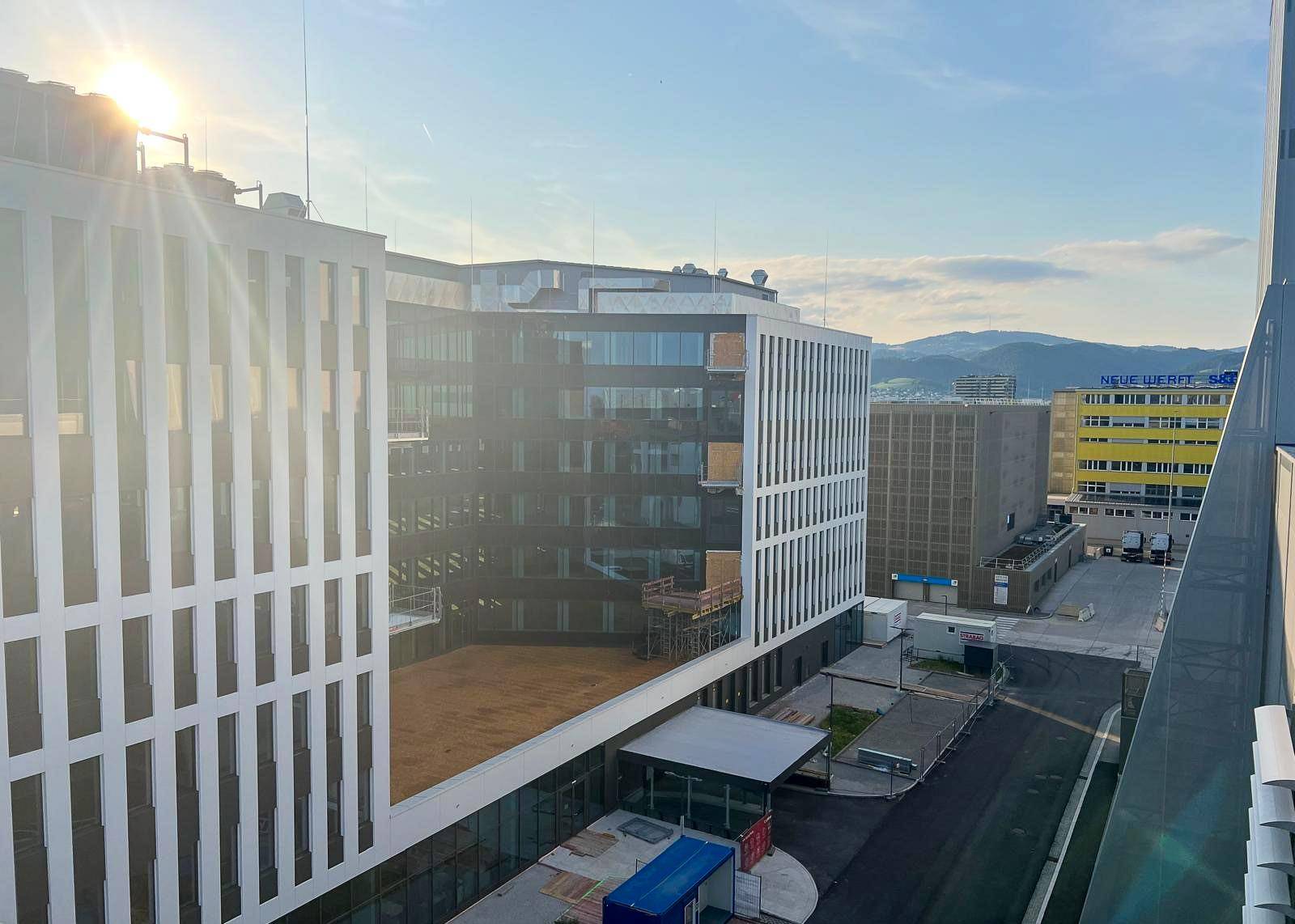 Eine Ansicht mehrerer moderner Bürogebäude mit markanten Fassaden unter blauem Himmel.