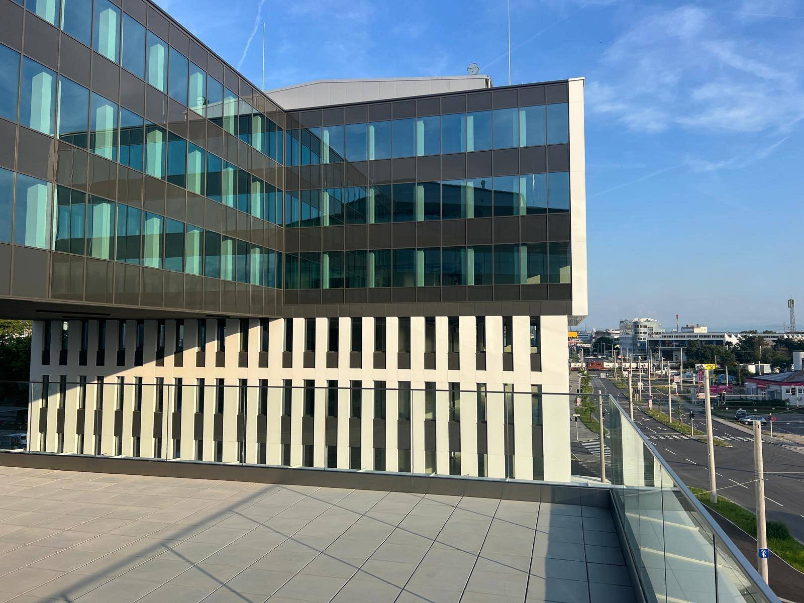 Eine moderne Terrasse mit Glasgeländer bietet einen weiten Blick auf die Stadt und die Umgebung.