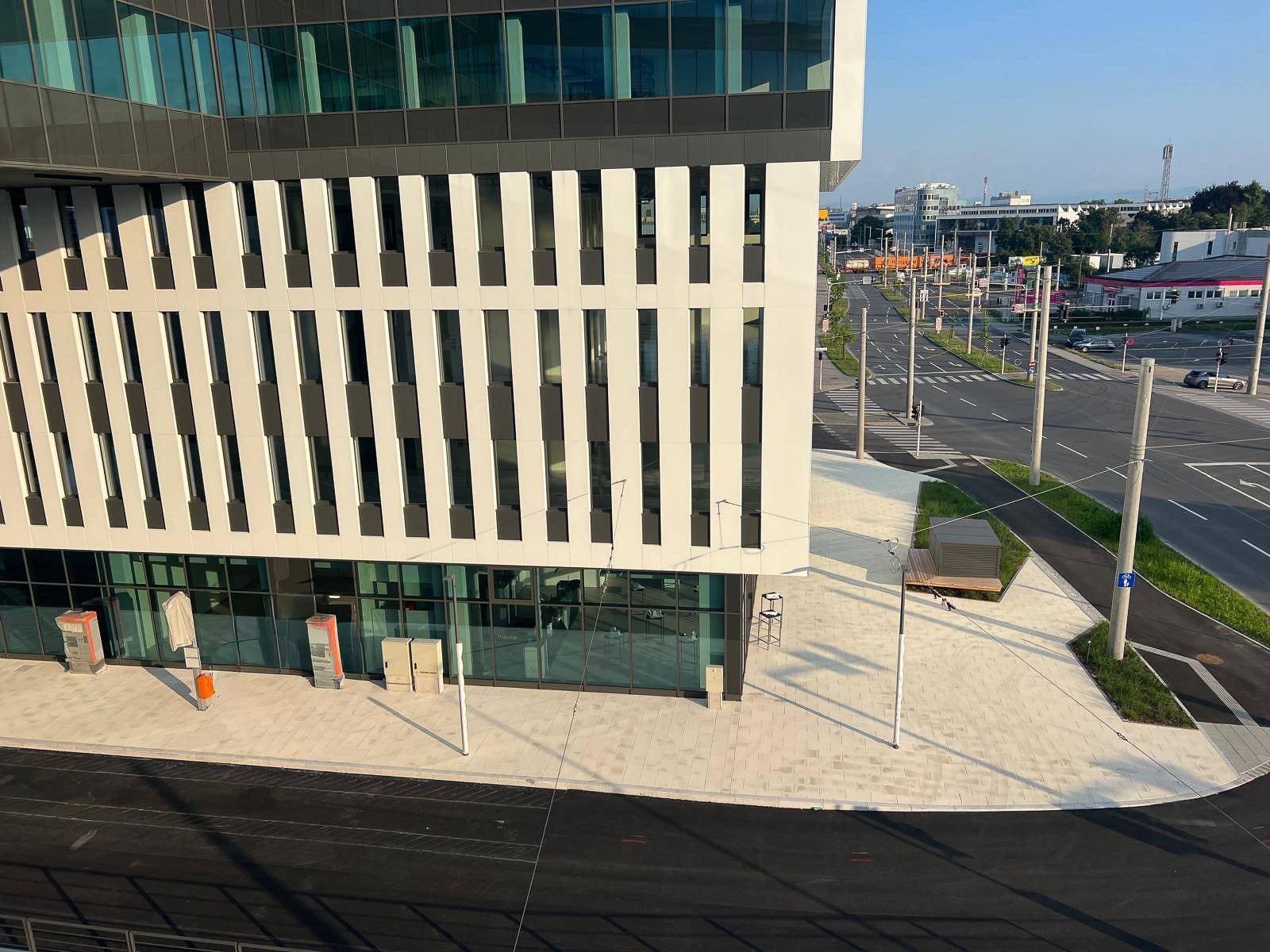 Die moderne Gebäudefassade mit großen Fenstern und einer breiten Straße davor.