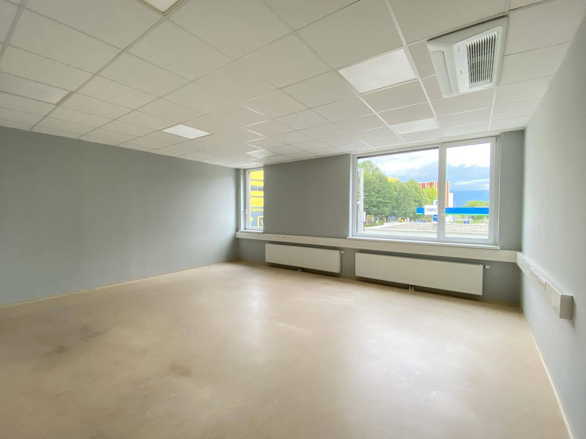 Geräumiger Büroraum mit großen Fenstern, die viel Tageslicht hereinlassen und eine weite Aussicht bieten.