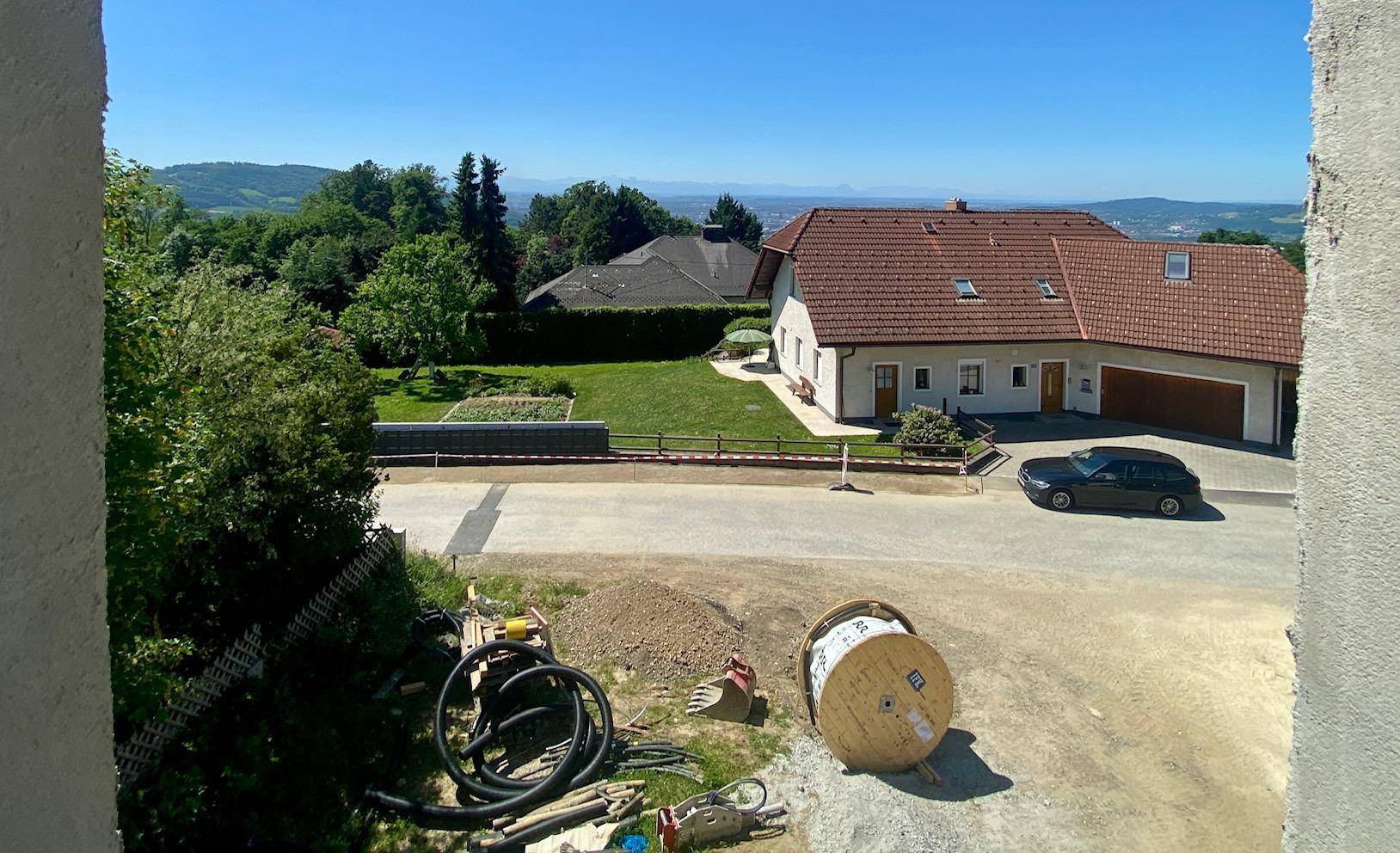 Ausblick aus einer Fensteröffnung im Rohbau auf die Nachbarschaft und die weite Landschaft.