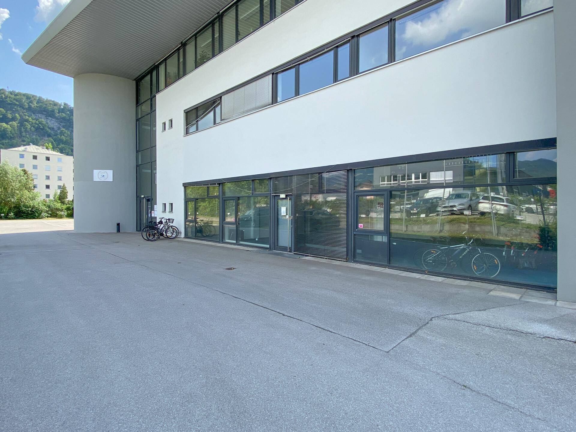 Moderne Geschäftsfassade mit großen Glasfenstern und Fahrrädern davor.