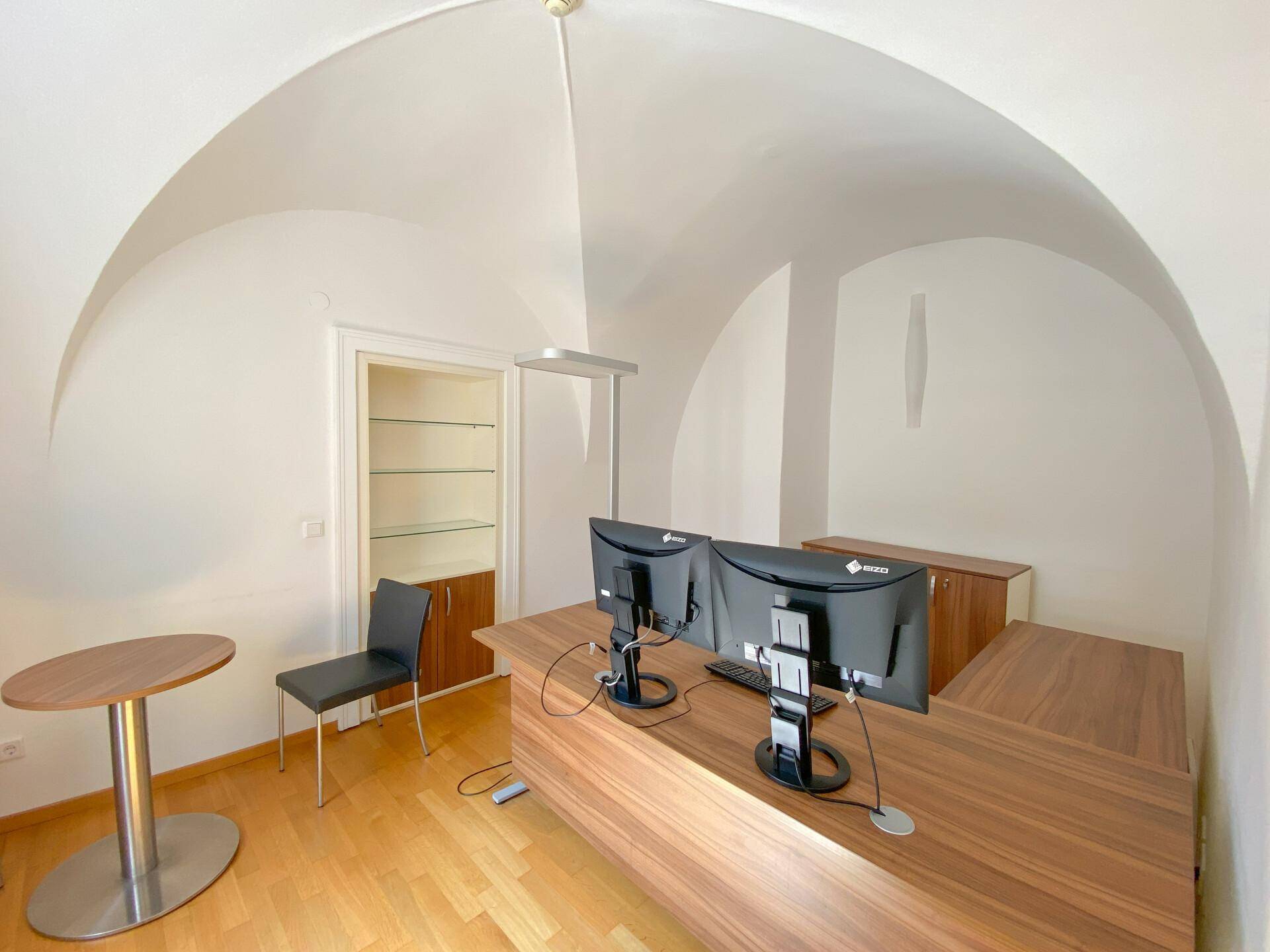 Büroraum mit beeindruckendem Gewölbedecke, modernem Schreibtisch und integriertem Regal für Stauraum.