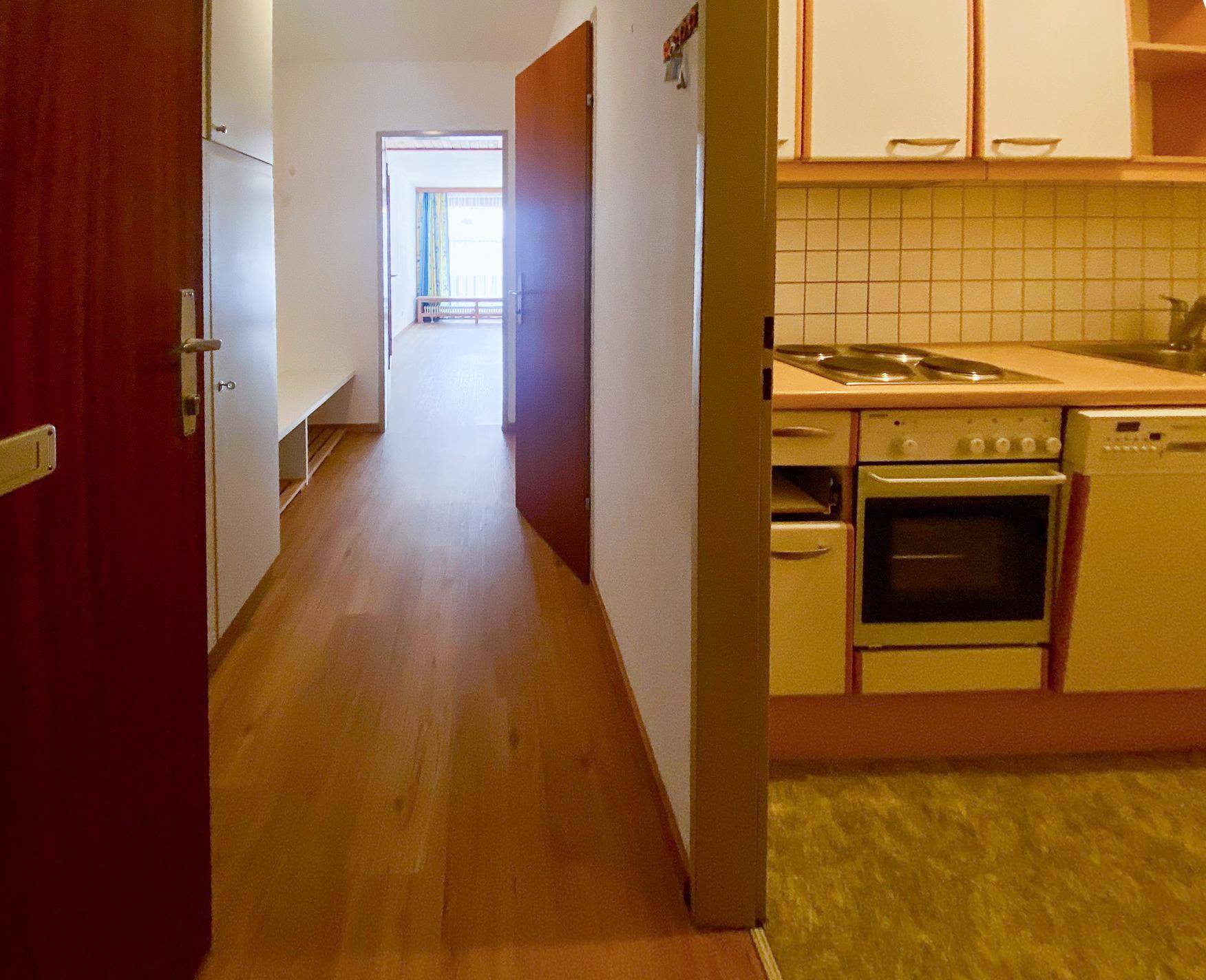 Flur mit Holzboden und Blick auf eine kleine Küchenzeile sowie weitere Zimmer.