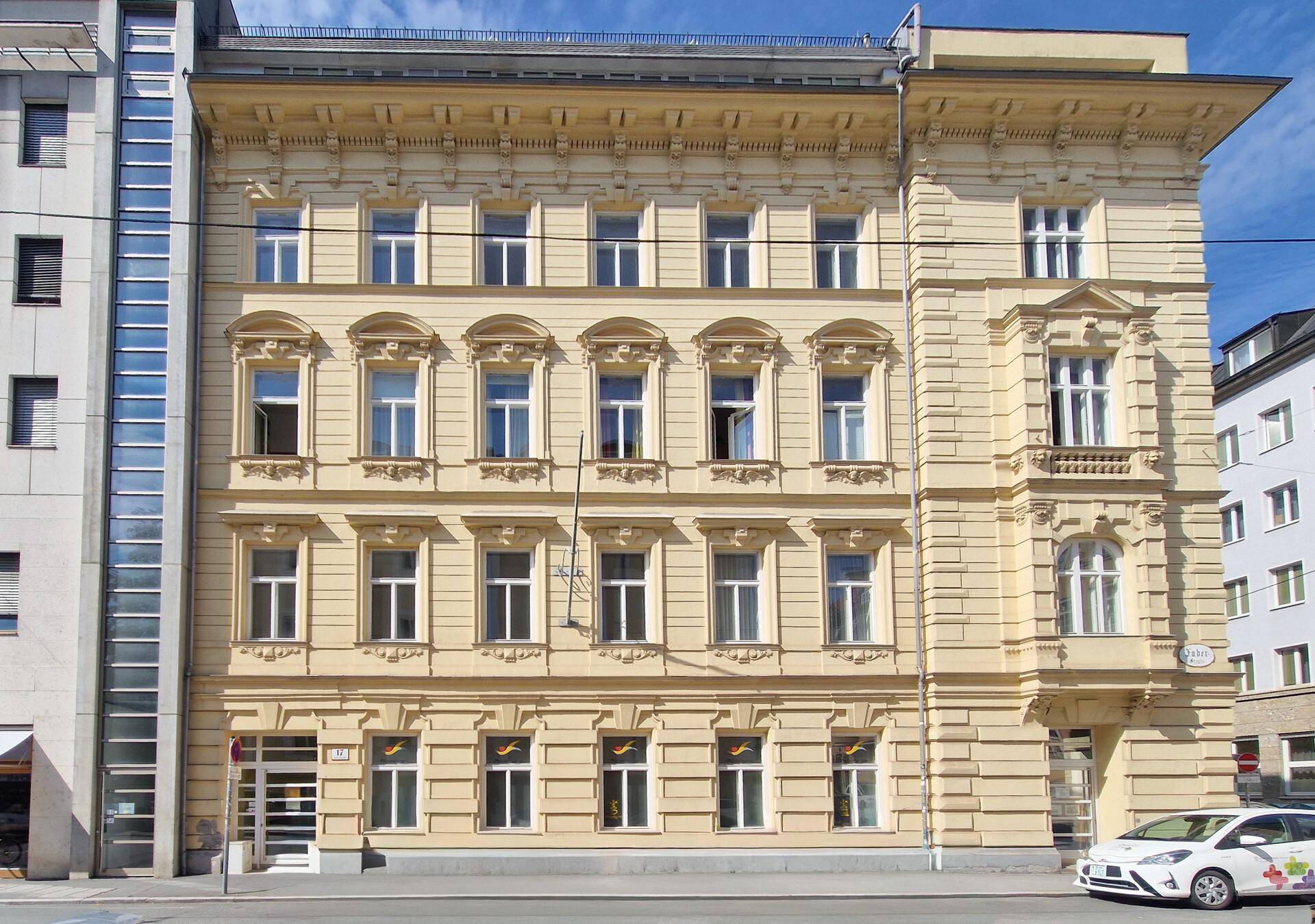 Historische Fassade eines Gebäudes mit vielen Fenstern und architektonischen Details.