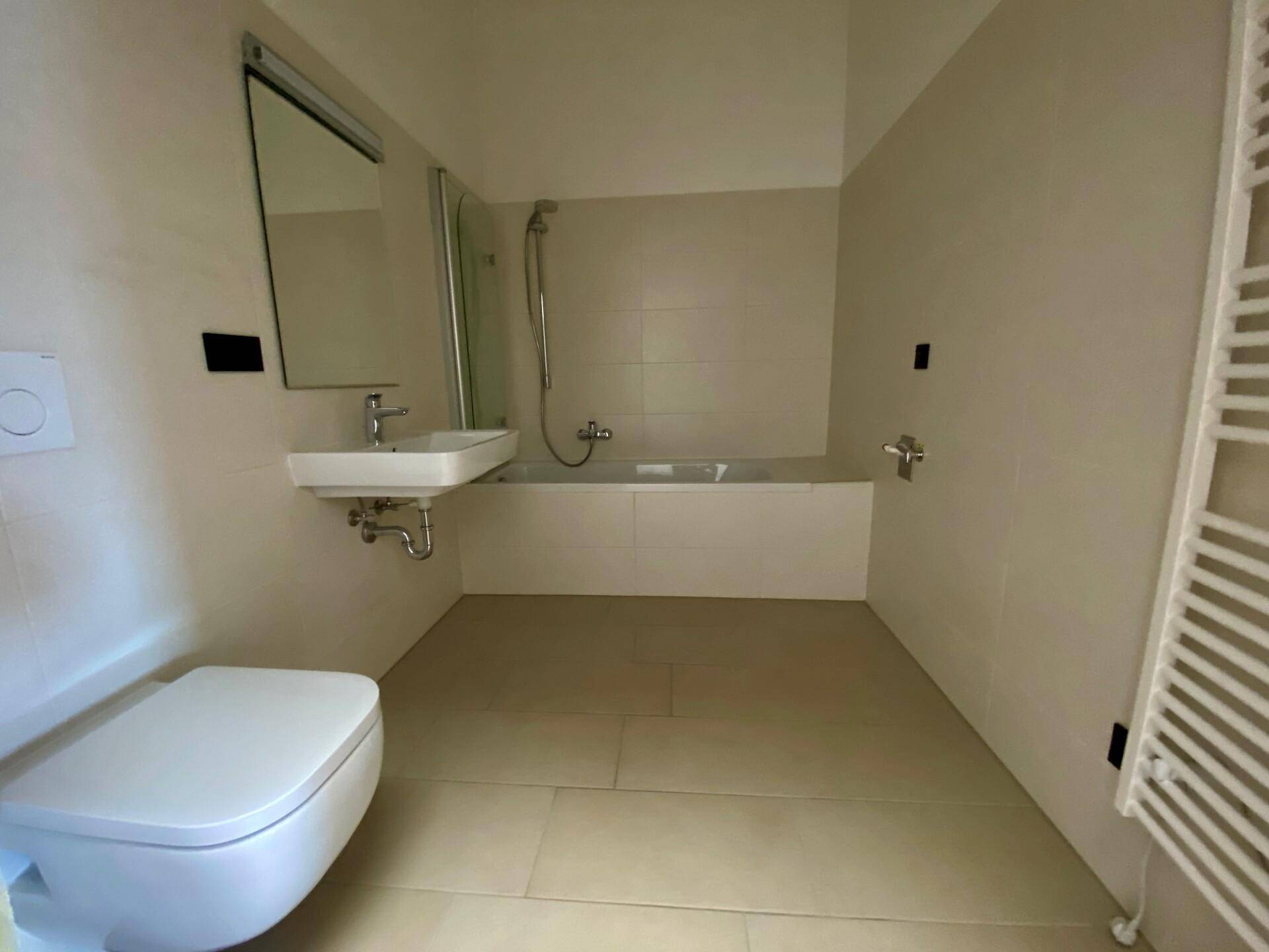 Modernes Badezimmer mit Badewanne, Dusche, WC, Waschbecken und beheiztem Handtuchhalter.