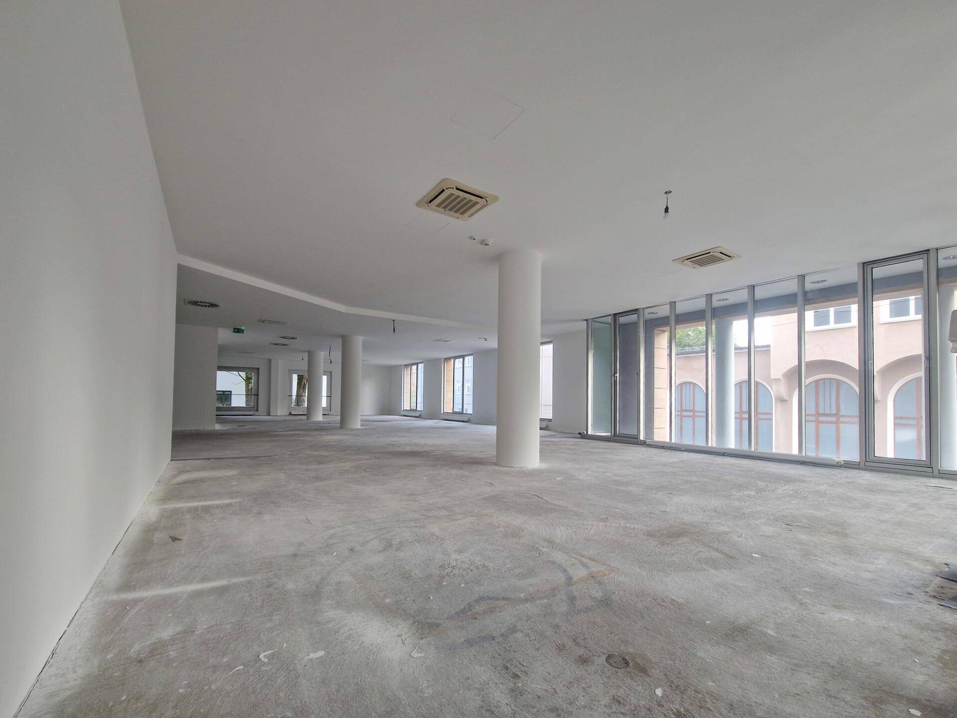 Weitläufiger, offener Bürobereich mit großen Fensterfronten und Säulen, bereit für den Ausbau.