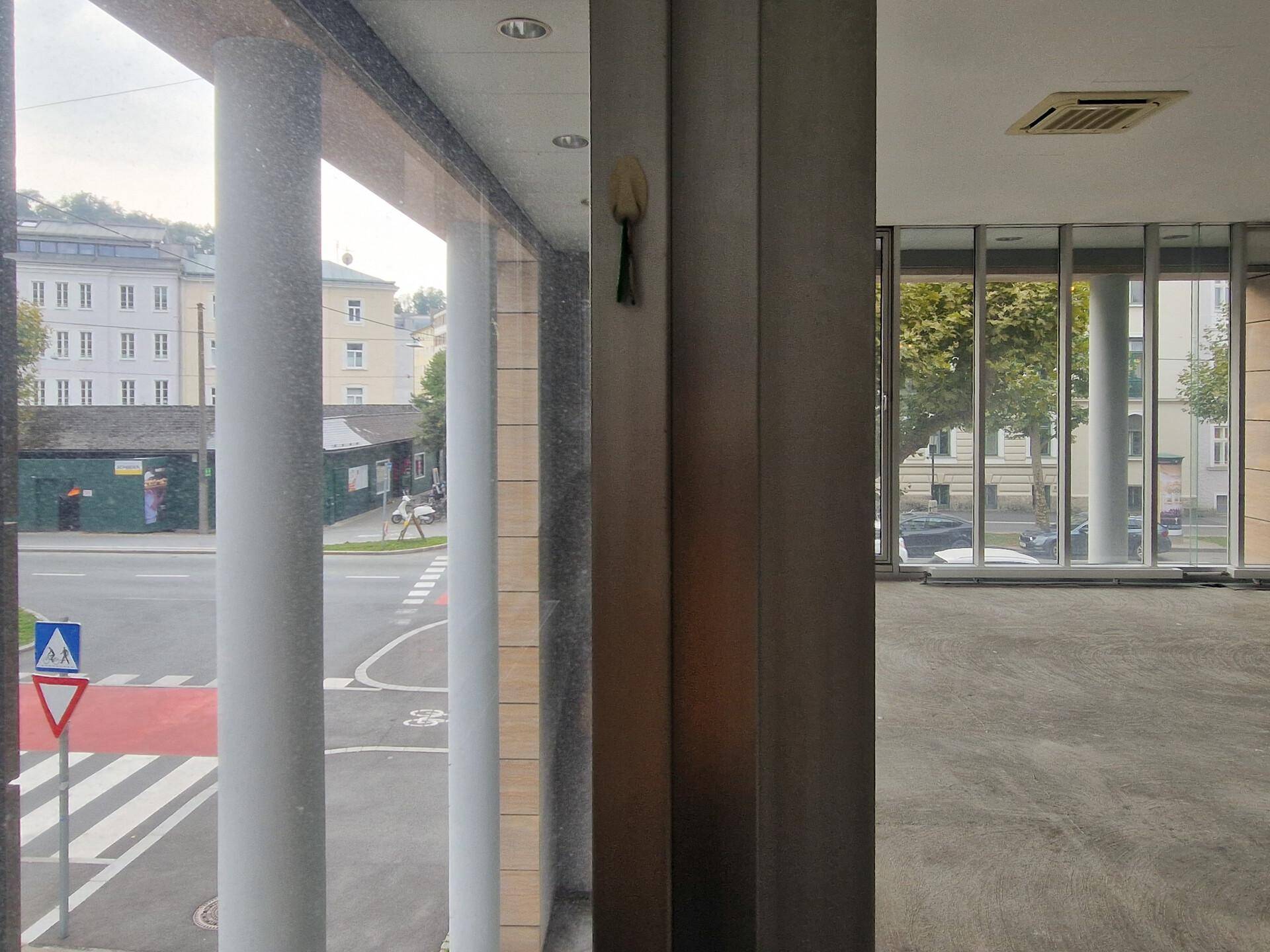 Blick aus dem Fenster eines Büroraums auf eine belebte Straße und umliegende Gebäude.