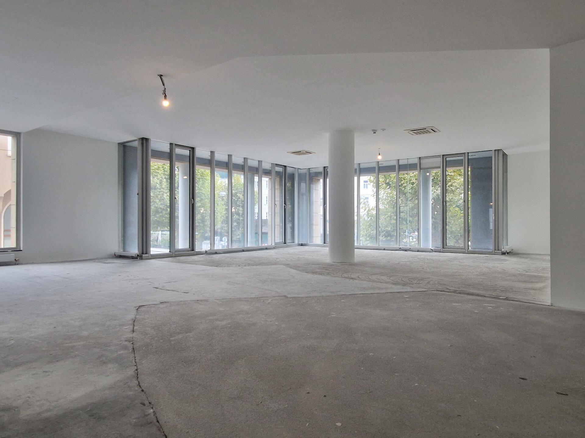 Geräumiger, offener Bürobereich mit durchgehenden Fensterfronten und Blick ins Grüne.