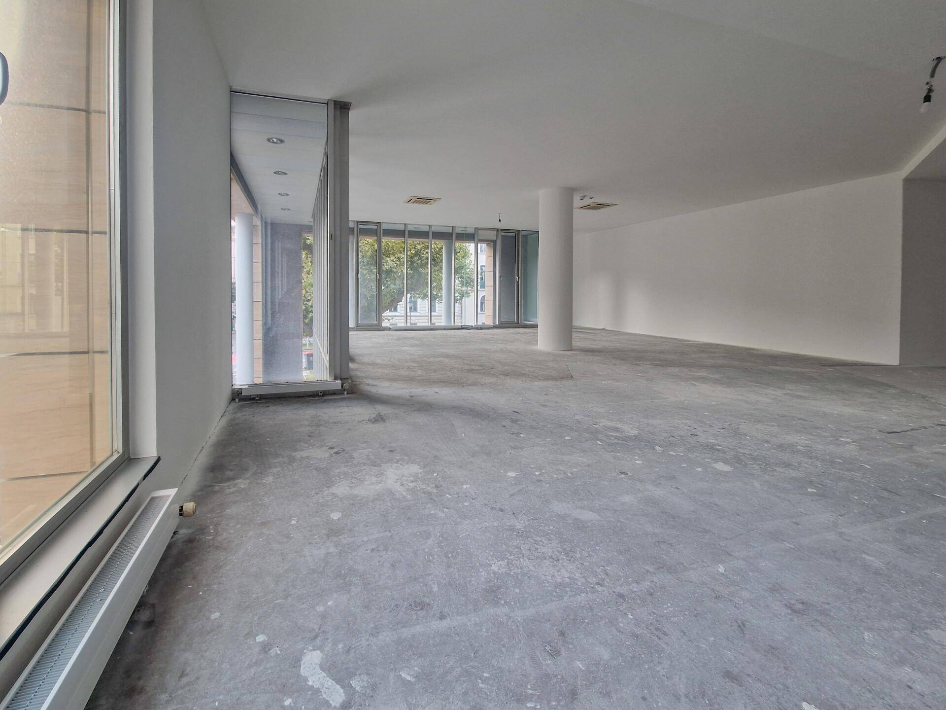 Offener Büroraum mit großen Fensterfronten, Säulen und Blick auf die Umgebung.