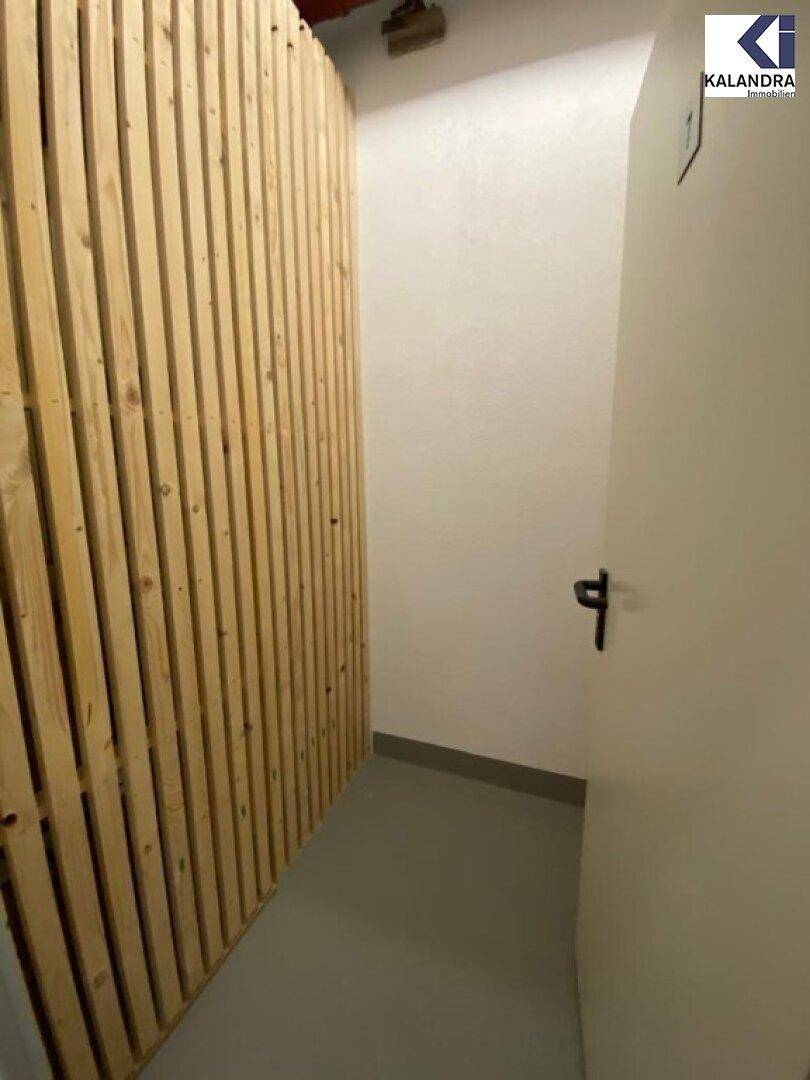Abstellraum mit Holzlattenwand und einfacher Tür.