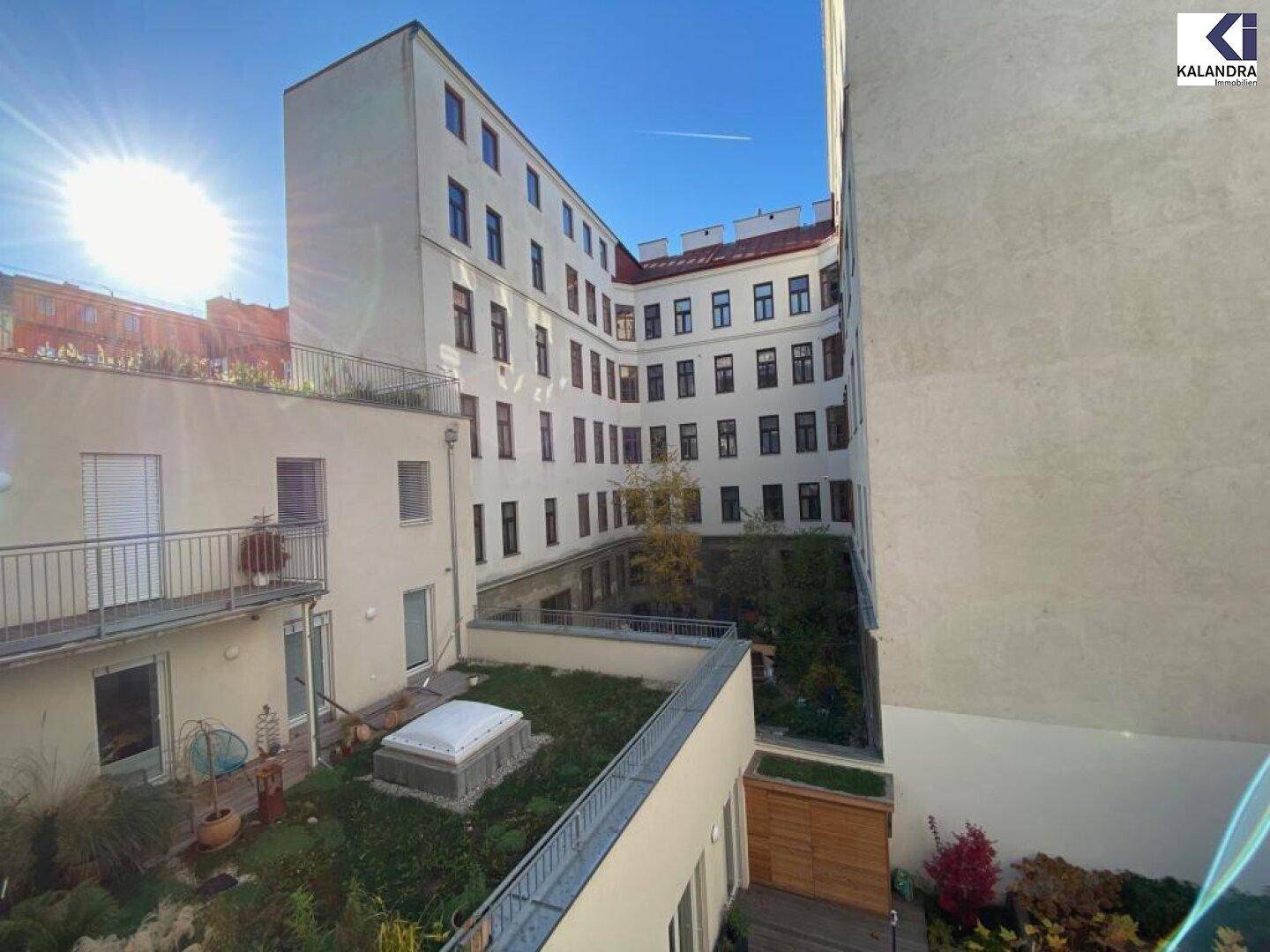Innenhofansicht des Gebäudes mit begrünten Dächern und sonnigem Himmel.