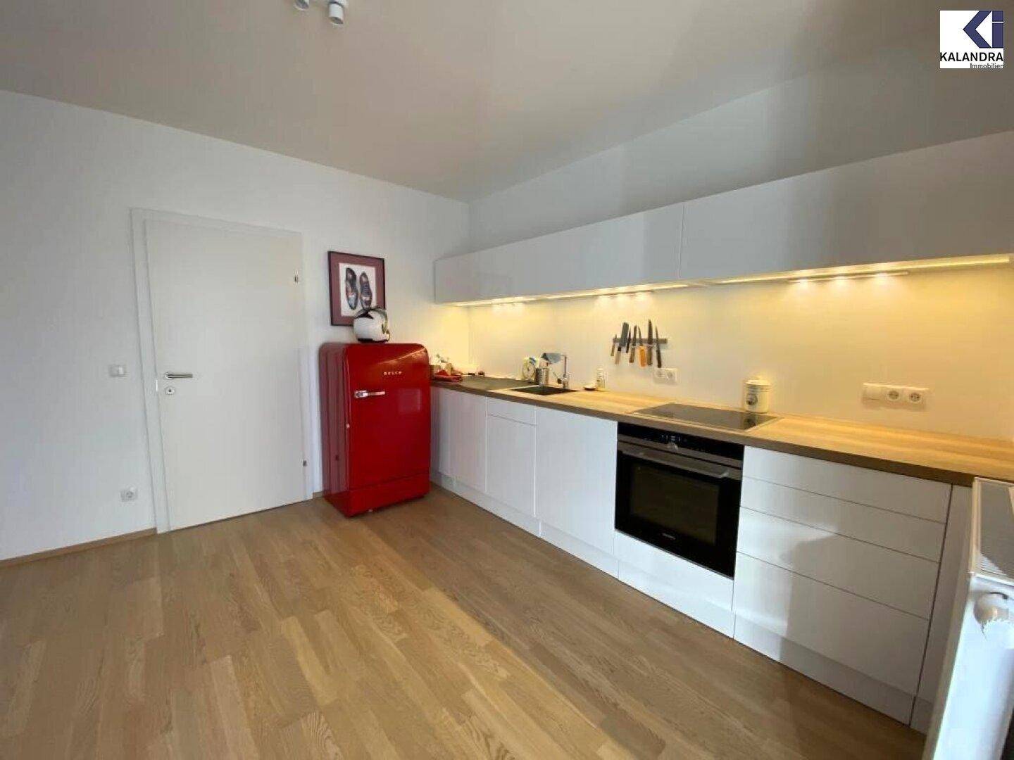 Helle Einbauküche mit weißen Schränken, Holztheke und modernem Herd.