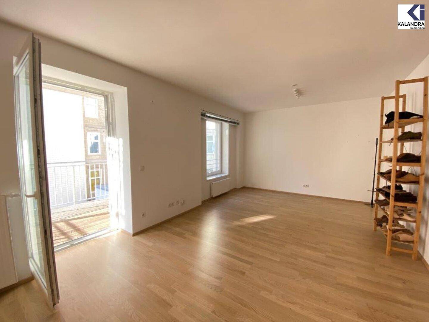 Heller Wohnbereich mit Zugang zum Balkon und Parkettboden.