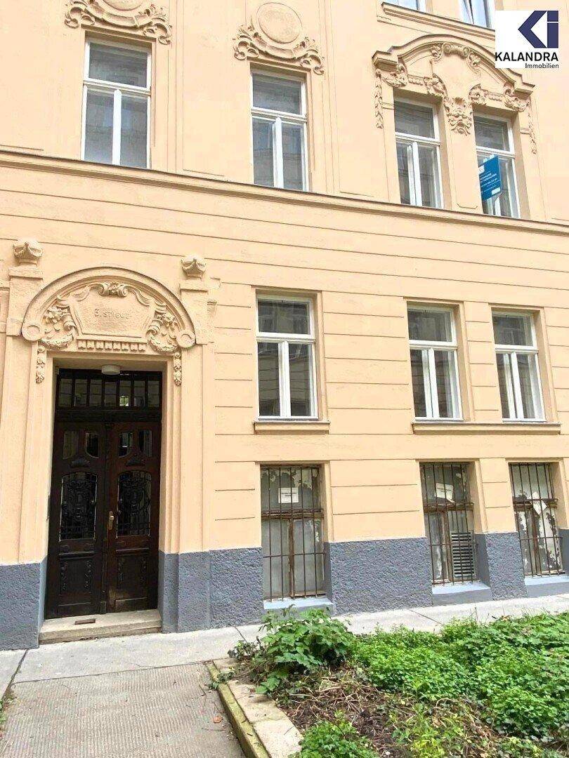 Historische Fassade eines Altbaus mit verzierten Fenstern, Eingangstür und einem kleinen Vorgarten.