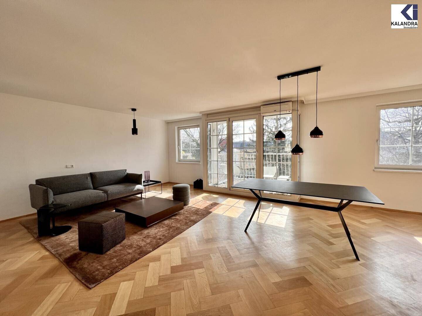 Offener Wohn-Essbereich mit Parkettboden, Esstisch und Zugang zum Balkon.