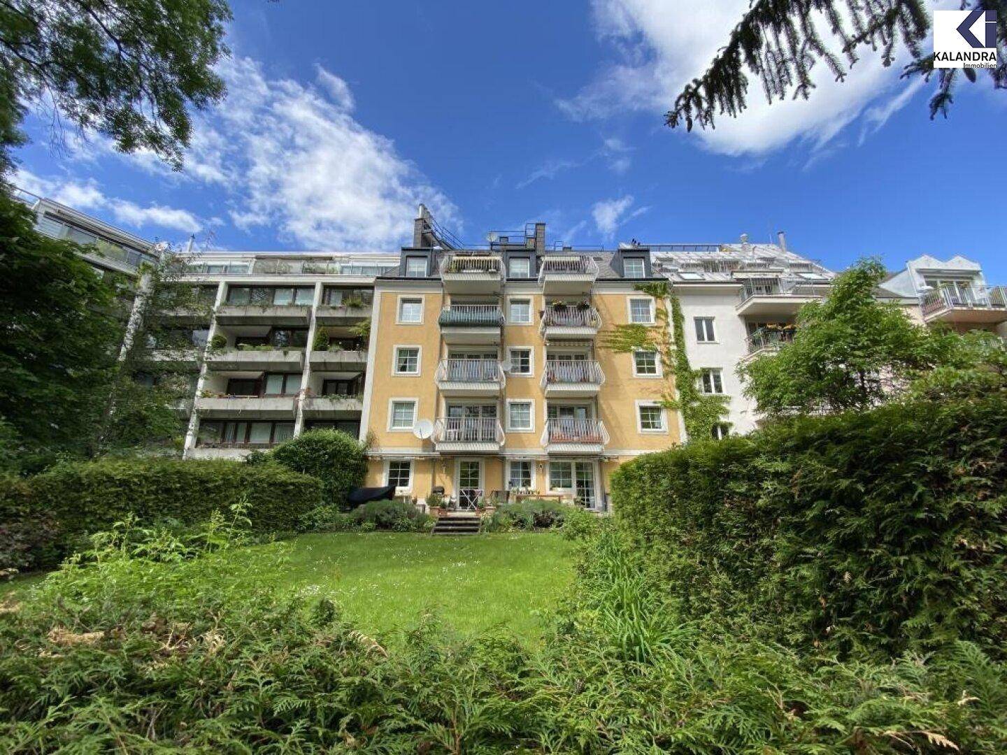 Rückansicht eines Mehrfamilienhauses mit Garten und mehreren Balkonen.