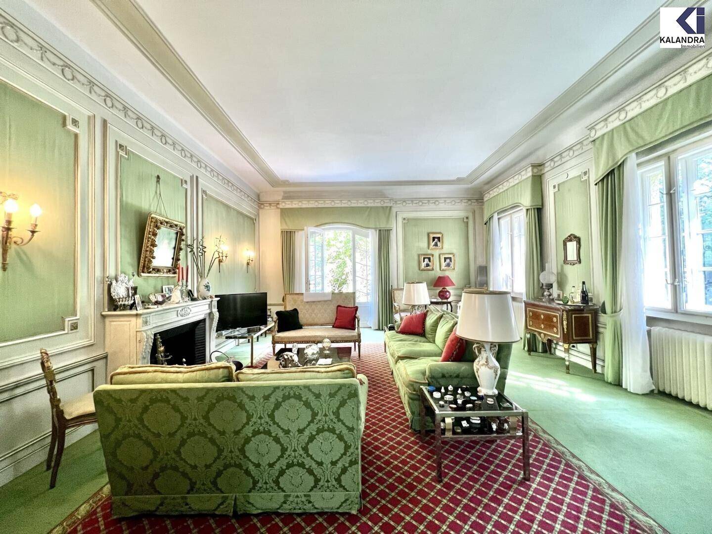 Elegantes Wohnzimmer mit Kamin, grünen Wänden und klassischer Einrichtung.