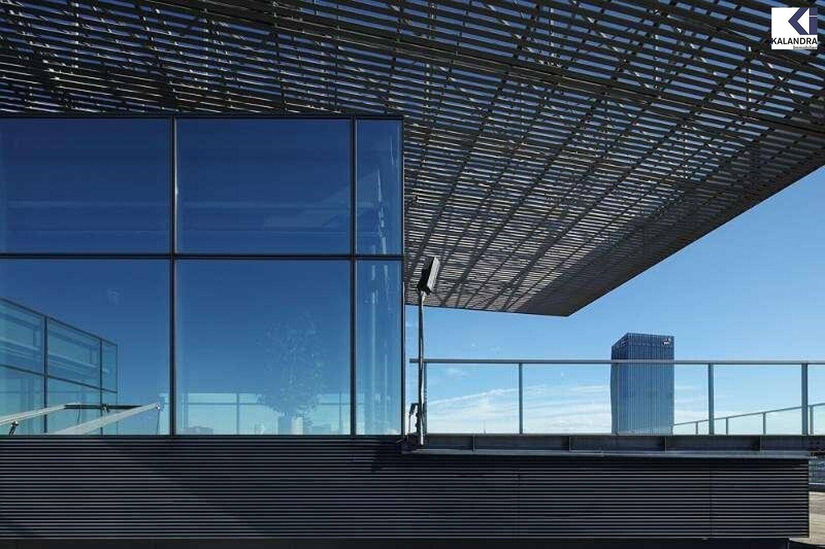 Detailansicht der modernen Glasfassade und der einzigartigen Überdachung des Gebäudes unter blauem Himmel.