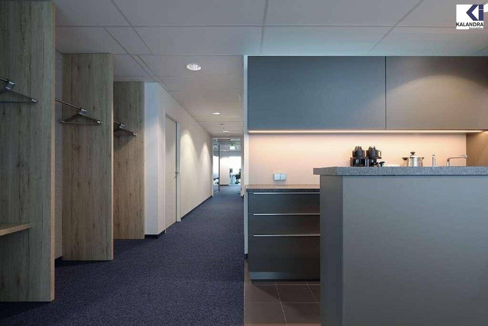 Moderner Bürogang mit Teppichboden und einer kleinen Küchenzeile für Kaffee und Getränke.