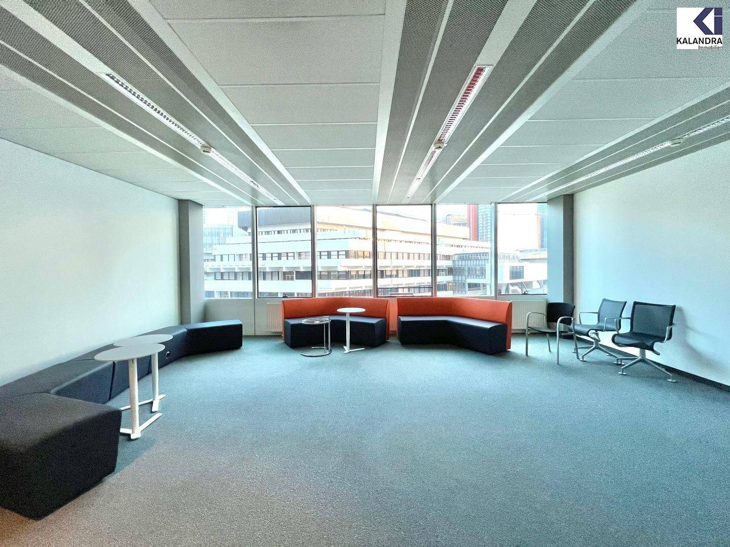 Moderner Loungebereich mit bequemen Sitzgelegenheiten und Teppichboden, ideal für informelle Treffen.