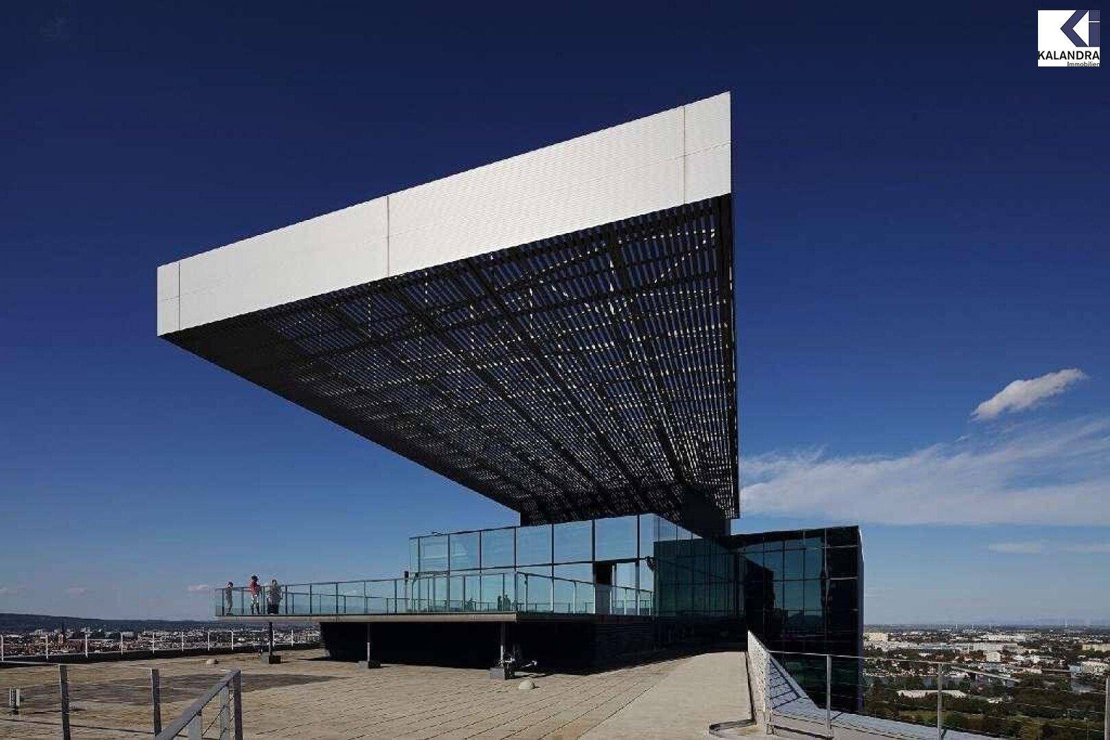 Beeindruckende moderne Architektur des Gebäudes mit einer weitläufigen Terrasse und weitem Blick über die Stadt.