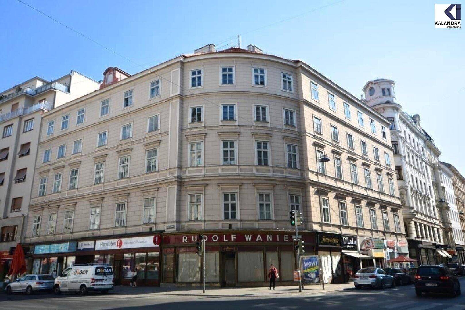 Historisches Eckgebäude in der Stadt mit mehreren Stockwerken und Geschäften im Erdgeschoss.