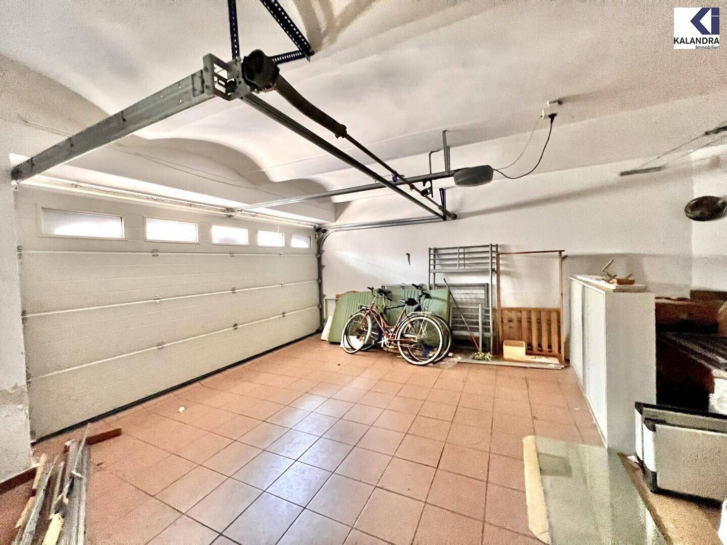 Geräumige Garage mit Fliesenboden, Garagentor und Abstellmöglichkeiten.