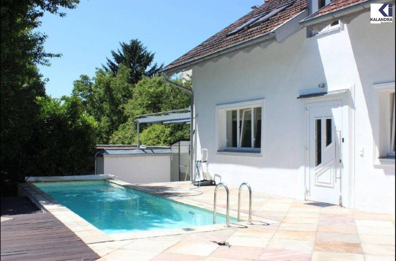 Außenbereich mit Swimmingpool, Steinterrasse und Zugang zum Haus.