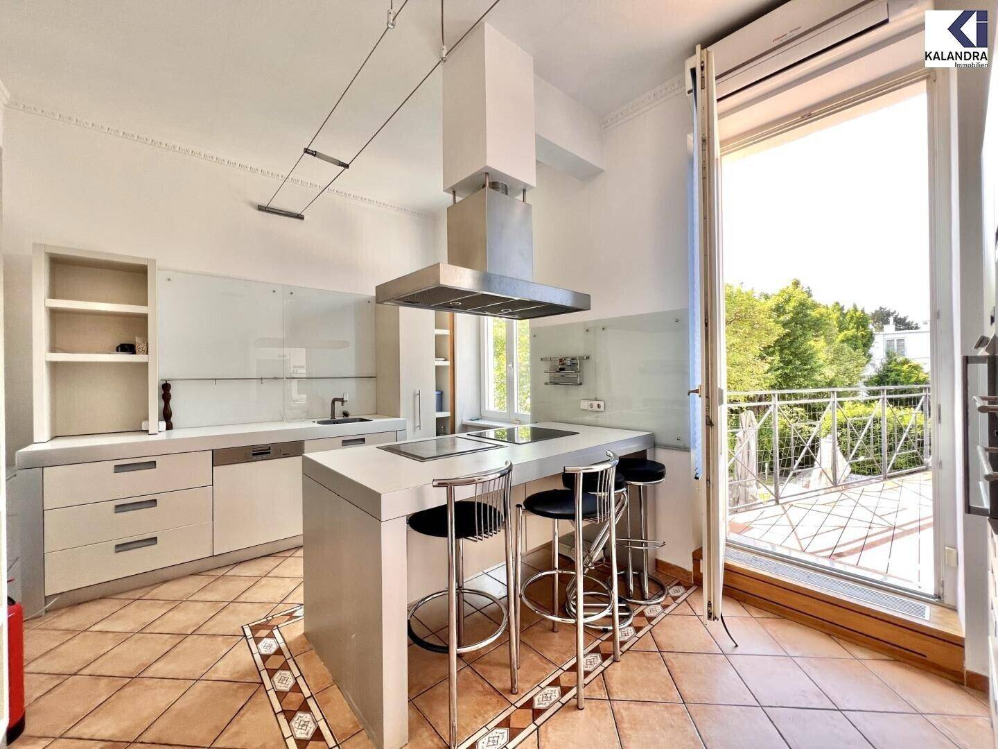 Moderne Küche mit Kochinsel, Terrakottafliesen und Zugang zu einem französischen Balkon.