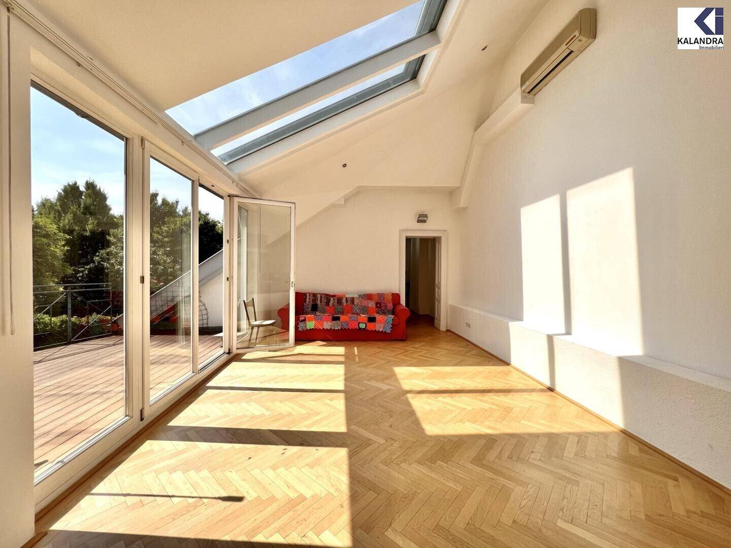 Heller Wohnbereich im Dachgeschoss mit Zugang zur Terrasse und großen Glasfronten.