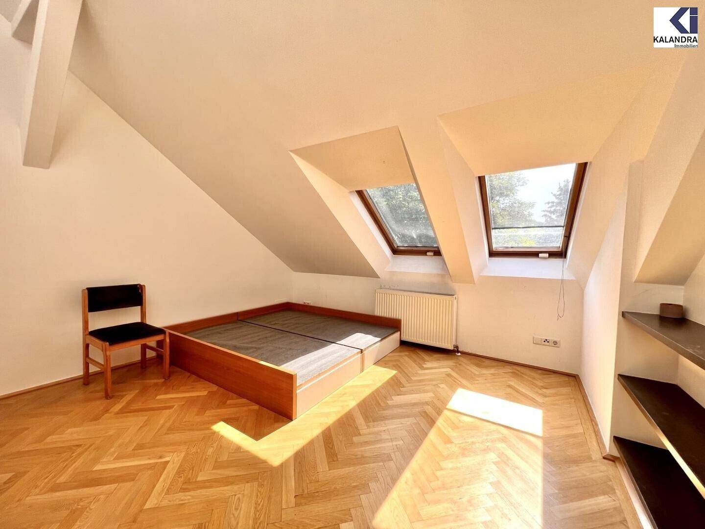 Helles Schlafzimmer im Dachgeschoss mit Parkettboden und zwei Dachfenstern.