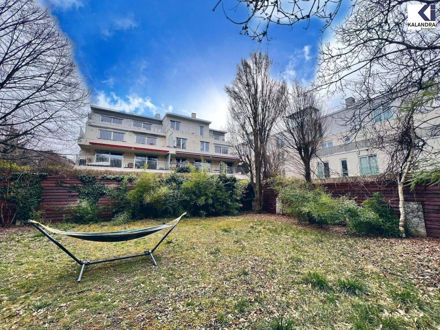 Großer Garten mit Hängematte, Bäumen und Blick auf ein Mehrfamilienhaus.