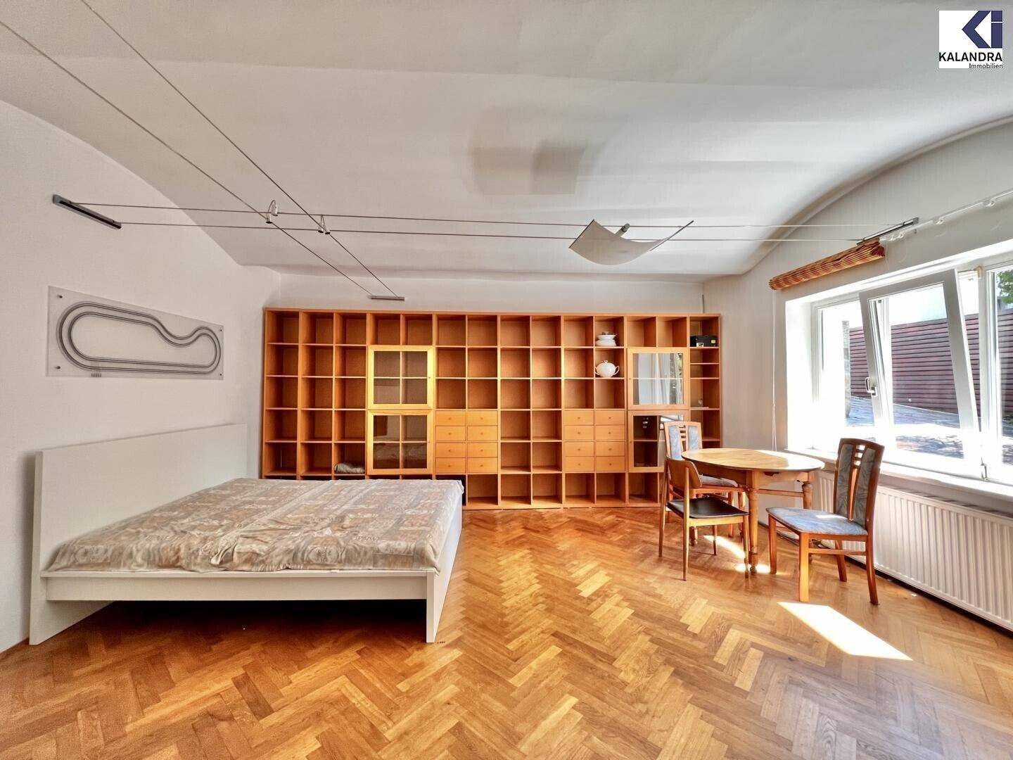 Geräumiges Schlafzimmer mit Parkettboden, Einbauregalen und viel Tageslicht.