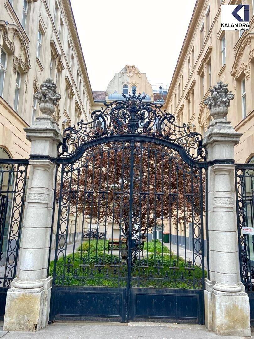 Historisches schmiedeeisernes Tor, das den Zugang zu einem begrünten Innenhof eines Altbaus gewährt.