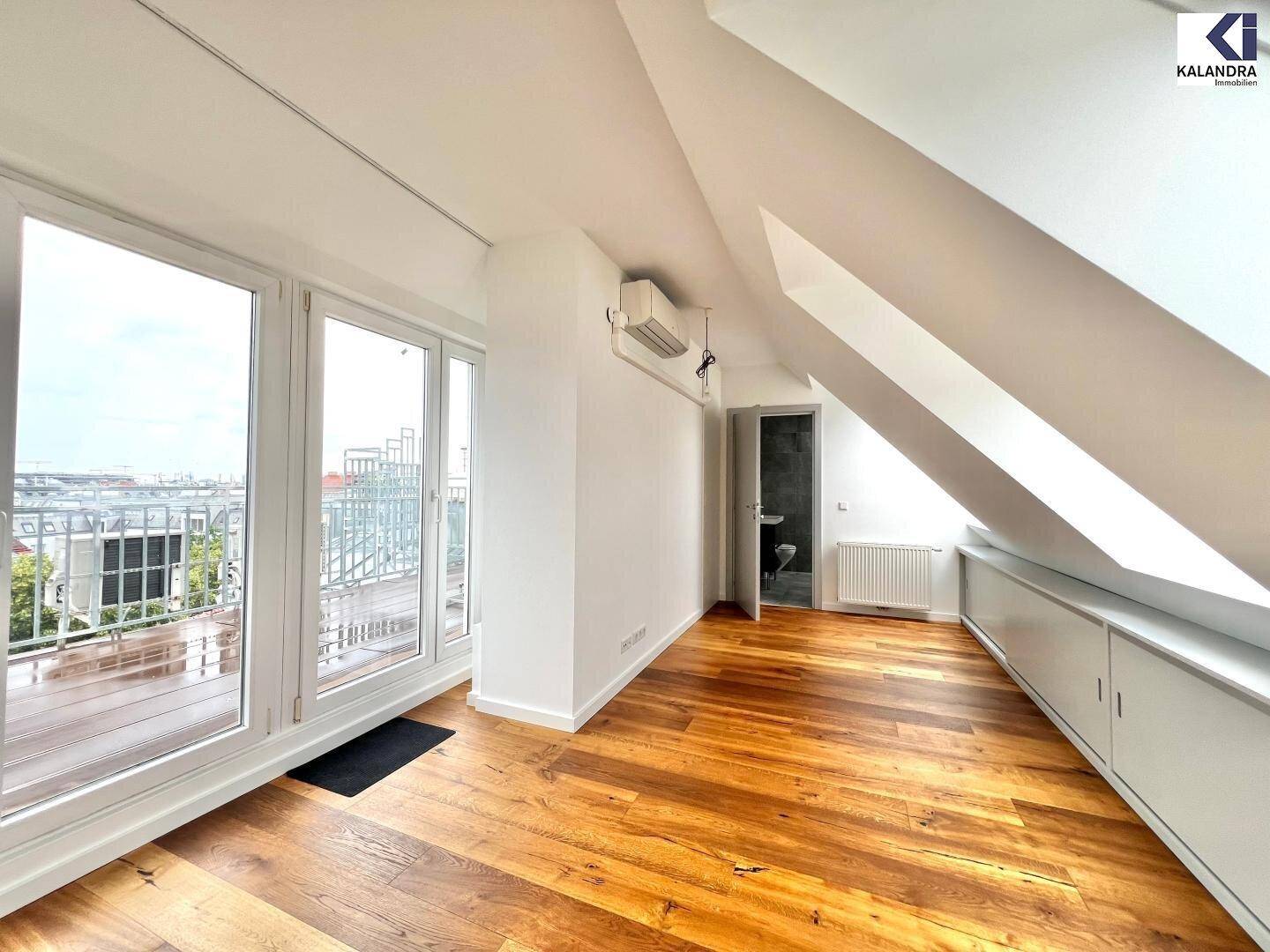 Heller Dachgeschossraum mit Holzboden, Zugang zur Terrasse und praktischen Einbauschränken.